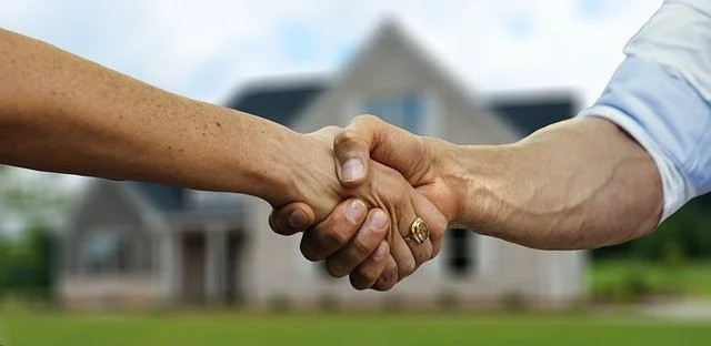 People shaking hands in front of the house.