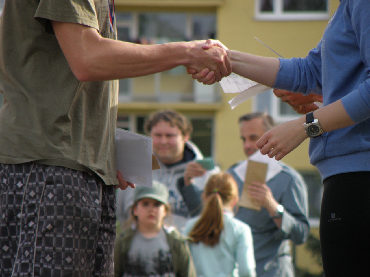 People shaking hands in front of a house.